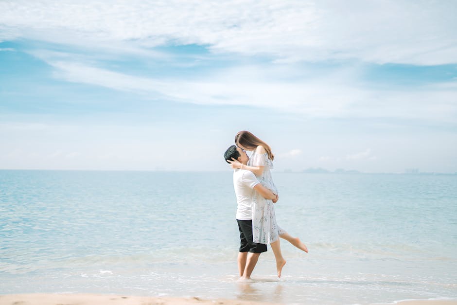 Full body side view of faceless couple in summer clothes hugging on beach near sea under blue cloudy sky in sunny summer day