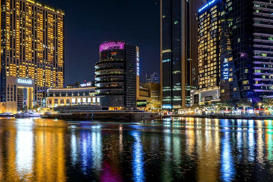 Illuminated high-rise buildings reflecting off Dubai's waterfront at night. A vibrant cityscape showcasing urban elegance.