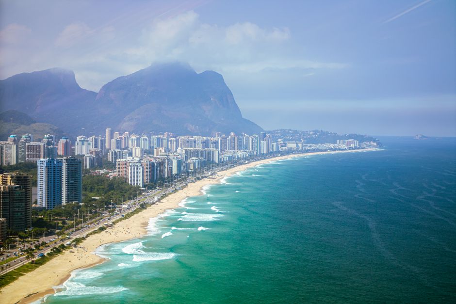 Stunning aerial view of Barra da Tijuca beach with city's skyline and mountains in Rio de